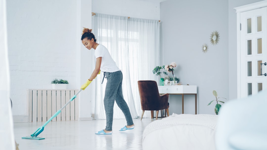 gallery-05 Pretty African American girl is mopping floor at home with flat plastic mop wearing gloves and wear-at-home clothing. Modern interiors, cleanness and young people concept.